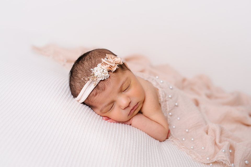 Newborn girl draped in peach blanket